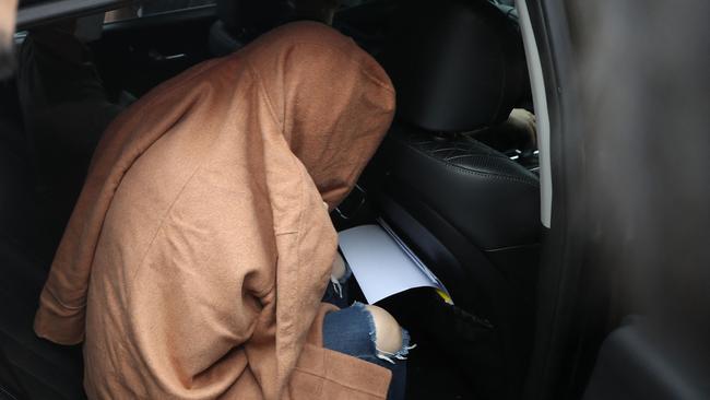 A 42-year-old woman, believed to be the mother of two children whose remains were found in suitcases in New Zealand, covers her head with a large brown coat at Ulsan Central Police Station after her arrest early morning in South Korea's southeastern city of Ulsan on September 15, 2022, before being transfered to Seoul to face extradition proceedings, police confirmed. (Photo by STRINGER / various sources / AFP) / - South Korea OUT / NO ARCHIVES - RESTRICTED TO SUBSCRIPTION USE