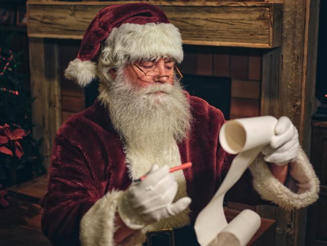 Santa Claus in a home, reading a Christmas list. istock image