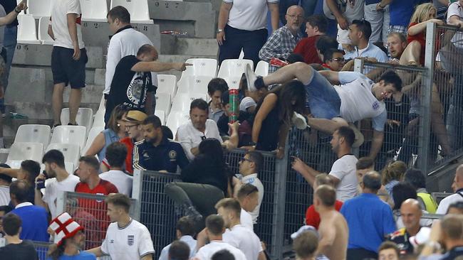 Supporters of England jump over a fence fleeing a scuffle that broke out.