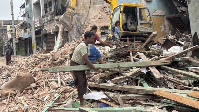 People clean debris from damaged buildings in the aftermath of the Myanmar earthquake in Naypyidaw on Monday. Picture: AP