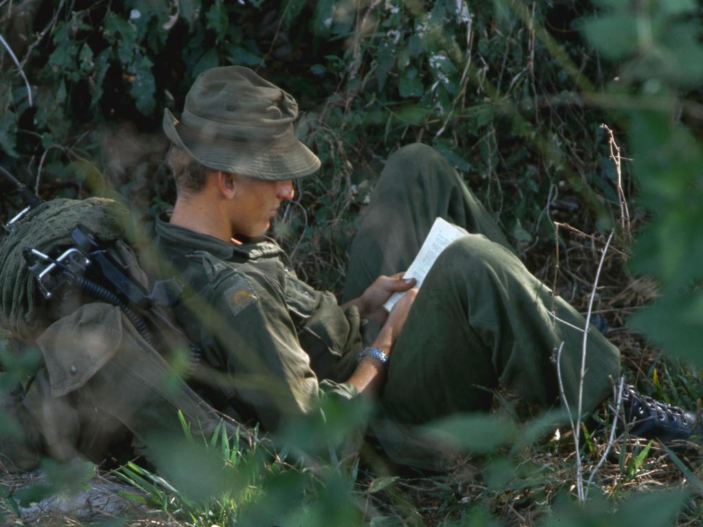 Books and battles ... an Australian soldier reads while taking a break near Bien Hoa, Vietnam, in 1965. Picture: Tim Page/Corbis via Getty Images.