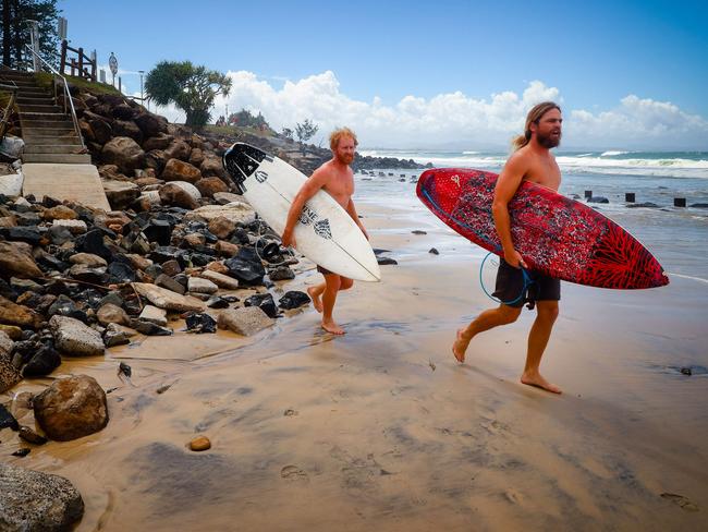 Two surfers negotiate massive beach erosion in the wake of cyclonic conditions at Byron Bay Main Beach on December 15, 2020, after wild weather lashed Australia's Northern New South Wales and South East Queensland with heavy rain, strong winds and king tides. (Photo by Patrick HAMILTON / AFP)