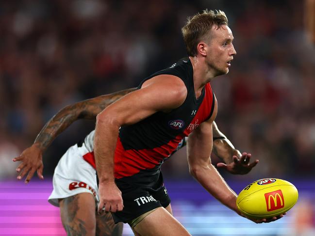 MELBOURNE, AUSTRALIA - MARCH 30: Darcy Parish of the Bombers handballs whilst being tackled during the round three AFL match between Essendon Bombers and St Kilda Saints at Marvel Stadium, on March 30, 2024, in Melbourne, Australia. (Photo by Quinn Rooney/Getty Images)
