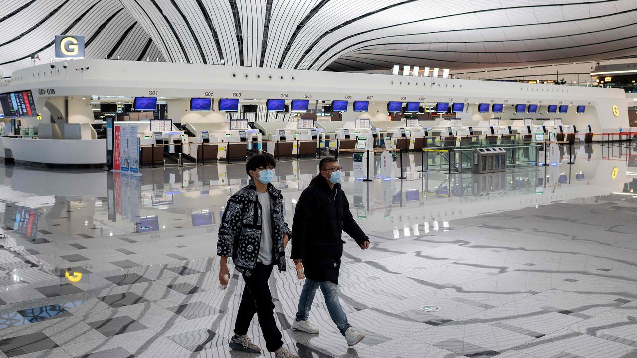 Two men walk through the nearly empty terminal at Daxing International Airport in Beijing. Picture: Nicolas Asfouri/AFP