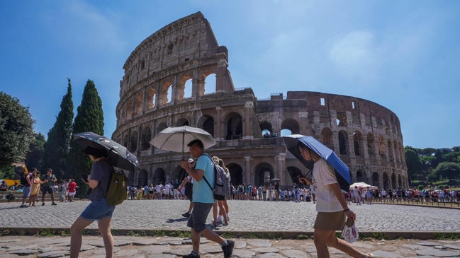 Tourists at the Colosseum in Rome shelter from the sun using umbrellas as temperatures rise above 40C. Picture: Alamy/The Times