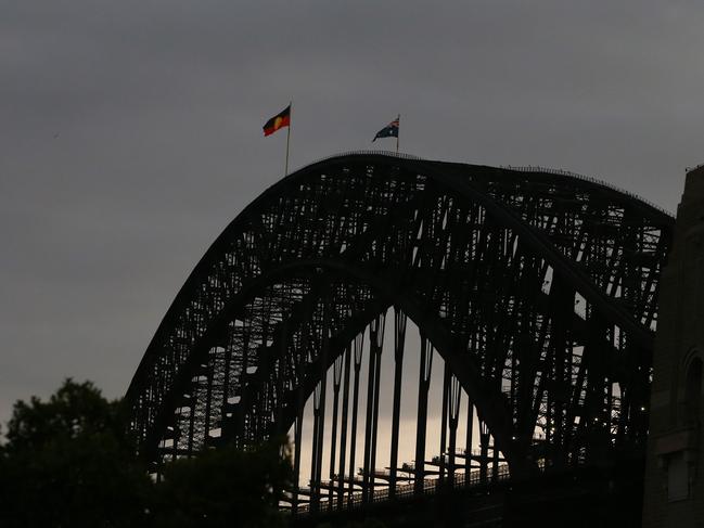 SYDNEY, AUSTRALIA - JANUARY 26: The Aboriginal flag is seen alongside the Australian flag on top of the Harbour Bridge on January 26, 2022 in Sydney, Australia. Australia Day, formerly known as Foundation Day, is the official national day of Australia and is celebrated annually on January 26 to commemorate the arrival of the First Fleet to Sydney in 1788. Indigenous Australians refer to the day as 'Invasion Day' and there is growing support to change the date to one which can be celebrated by all Australians. (Photo by Lisa Maree Williams/Getty Images)