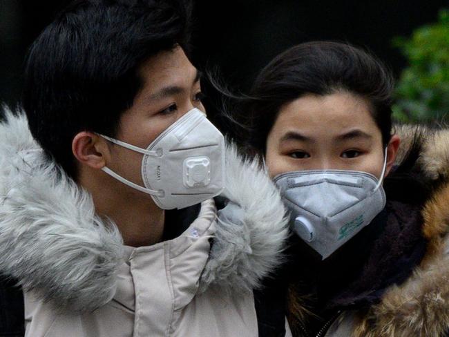 A couple wearing protective facemasks walks along a street in Shanghai on February 15, 2020. - The death toll from the new coronavirus outbreak jumped past 1,500 in China as France reported the first fatality outside Asia, fuelling global concerns about the epidemic (Photo by NOEL CELIS / AFP)