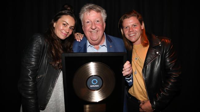 Denis Handlin (centre) with Sony Music artists Amy Shark and Conrad Sewell at the Queensland Music Awards in March 2020, pictured with Handlin’s honorary award, which was revoked by QMusic in October 2021.