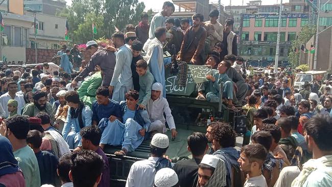 Taliban fighters and local people sit on an Afghan National Army humvee vehicle on a street in Jalalabad province. Picture: AFP