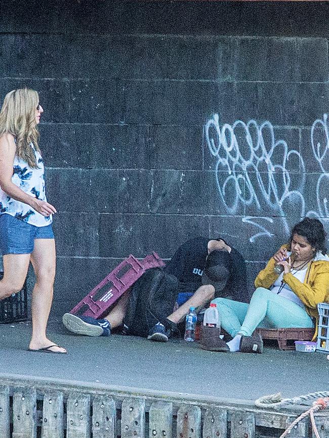 A woman smokes a bong alongside the Yarra River underneath Riverland Bar as Australian Open Tennis patrons walk past. Picture: Mark Stewart