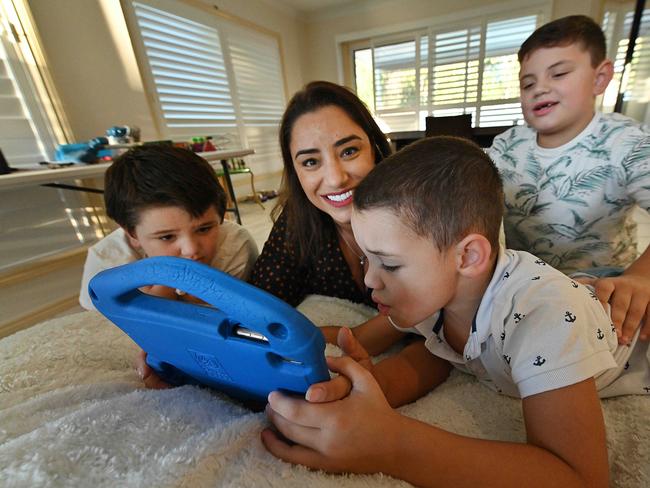 09/04/2021: Katherine Peereboom and her boys, L-R Joshua, 6, Tyler, 5, and Oliver, 7, with their iPads and mums iPhone at their home on the Gold Coast. The boys have all been diagnosed with autism, they love their devices and Katherine is sometimes on edge making sure what they view is safe and managing their time spent on the app. . Lyndon Mechielsen/The Australian