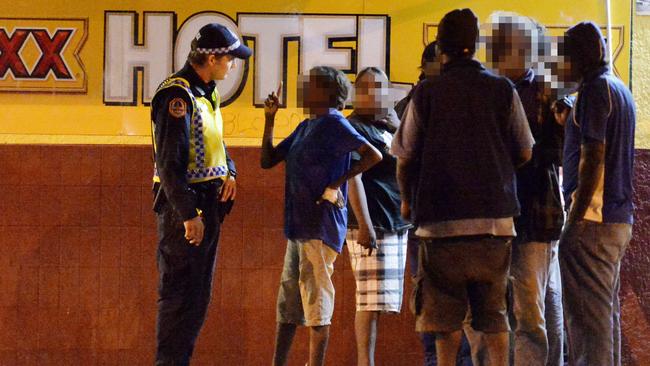 A police officer talks to locals outside a bottle shop at Peko Park in the centre of town in Tennant Creek.