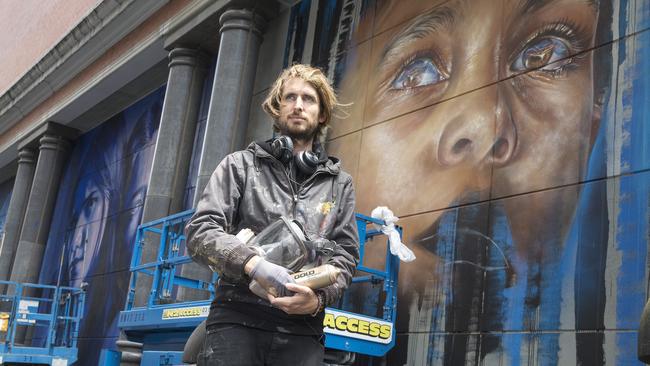 Matt Adnate with his portrait of a young indigenous boy. Picture: Michael Klein