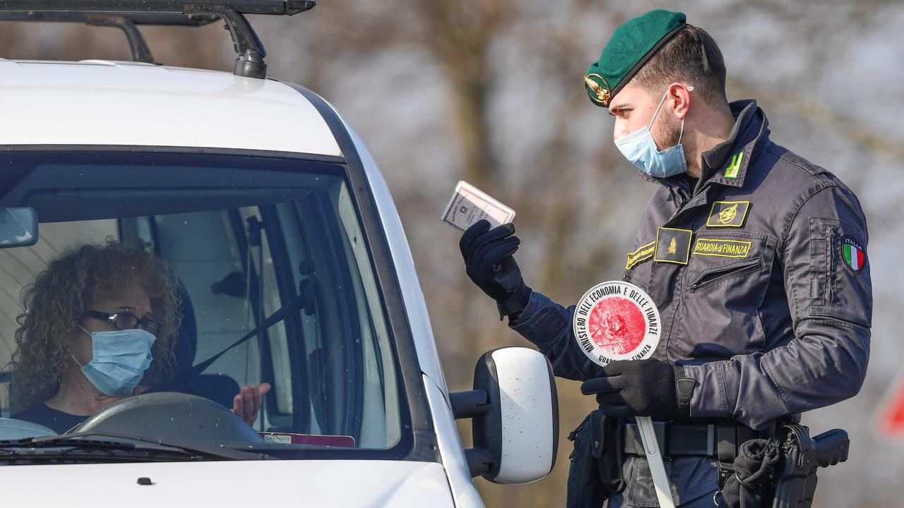 An Italian guard checks drivers at a checkpoint outside Zorlesco, southeast of Milan. Picture: AFP/Miguel MEDINA