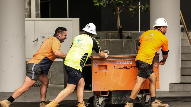 Workers leave the Probuild worksite on 443 Queens St on Wednesday. Picture: Zak Simmonds