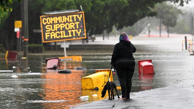 A woman walks her dog on a flooded road in Lismore, northern NSW, in March. Picture: Getty Images