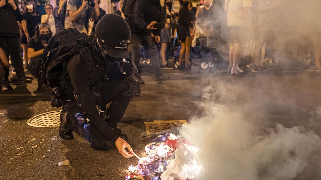 A protester lights a cigarette on a burning American Flag while marching with abortion-rights activists in Washington, DC. Picture: Getty