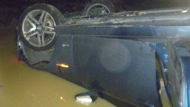 The car half submerged in the quarry waters.