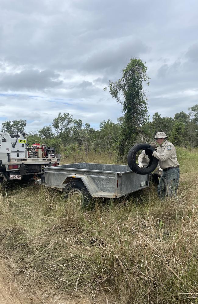 QPWS conservation officers remove illegally dumped tyres from beside a road in Townsville.