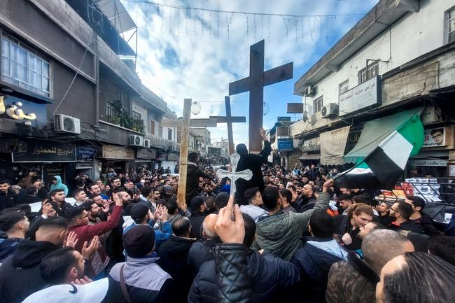 Christian Syrians lift crosses as they rally in Damascus to protest the burning of a Christmas tree near Hama