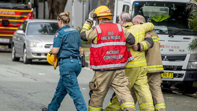 Fire fighters help another firefighter after exiting the house. Picture: Jerad Williams