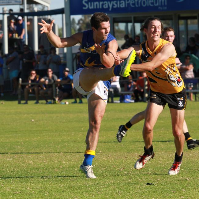 Irymple's Nick Pezzaniti gets his kick away under pressure from Red Cliff's Kieren Bell. Photographer: Glenn Milne