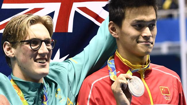 Australia's Mack Horton (C) holds the Australian flag as he poses on the podium with silver medallist China's Sun Yang.