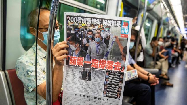 (FILES) A commuter reads a copy of the Apple Daily newspaper on a train in Hong Kong on August 11, 2020, a day after authorities conducted a search of the newspaper's headquarters after the company’s founder Jimmy Lai was arrested under the new national security law. Jailed pro-democracy media tycoon Jimmy Lai will go on trial for national security crimes in Hong Kong on December 18, 2023 having already spent three years behind bars and facing life in prison for widely condemned charges. (Photo by ISAAC LAWRENCE / AFP)