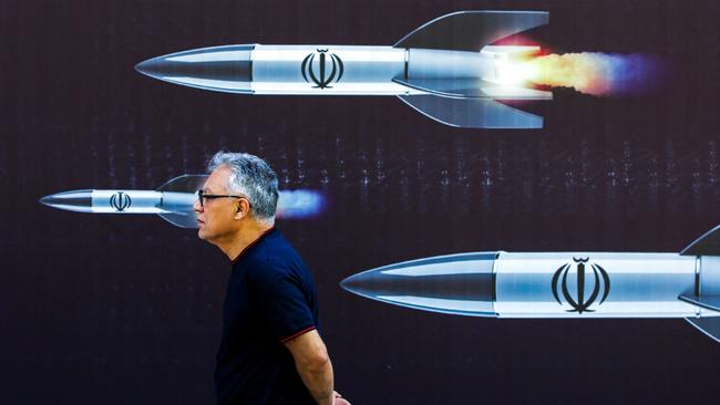 A man walks past a banner depicting missiles along a street in Tehran on April 19. Picture: AFP