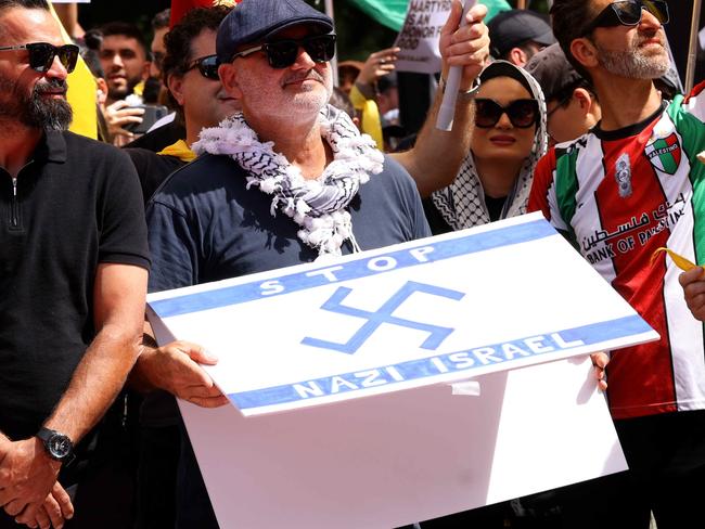 SYDNEY, AUSTRALIA - NewsWire Photos OCTOBER 6, 2024: A protester pictured holding  a flag that has a Nazi like symbol on it at the protest in Hyde Park. Protestors gather at Hyde Park in Sydney's CBD to demand an end to the ongoing war and Israel's current occupation of Gaza, and the escalating Israel-Lebanon conflict.Picture: NewsWire / Damian ShawAl Yazbek