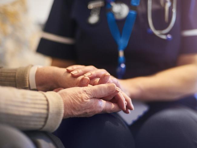 A female nurse consoles a senior patient at home, aged care generic