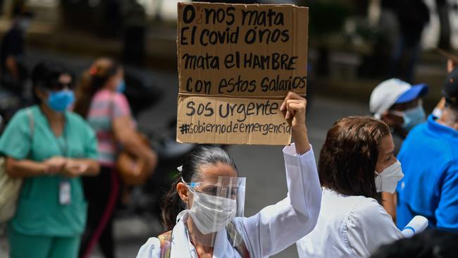 A health worker holds up a sign reading ‘COVID is not killing us, hunger is killing us with these wages’ during a protest for the lack of medicines, medical supplies, poor conditions in hospitals, and in demand of fairer salaries in Caracas. Picture: AFP