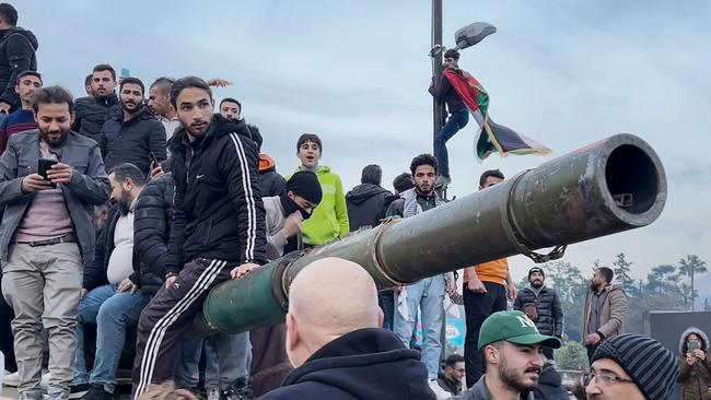 People sit on a tank as they gather at Umayyad Square in Damascus. Picture: AFPTV/AFP