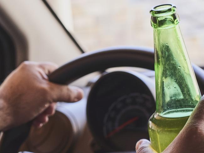 An unrecognizable man drinking beer while driving car. Concepts of driving under the influence, drunk driving or impaired driving. Drink driving generic. Picture: iSTOCK