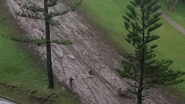 Kirra Hill has become a mudslide after the recent torrential rain, with kids using boards to slide down it.