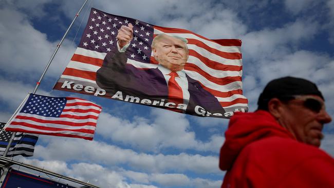 A Trump supporter walks past a flag featuring Donald Trump flying near his Mar-a-Lago home. Picture: Getty Images