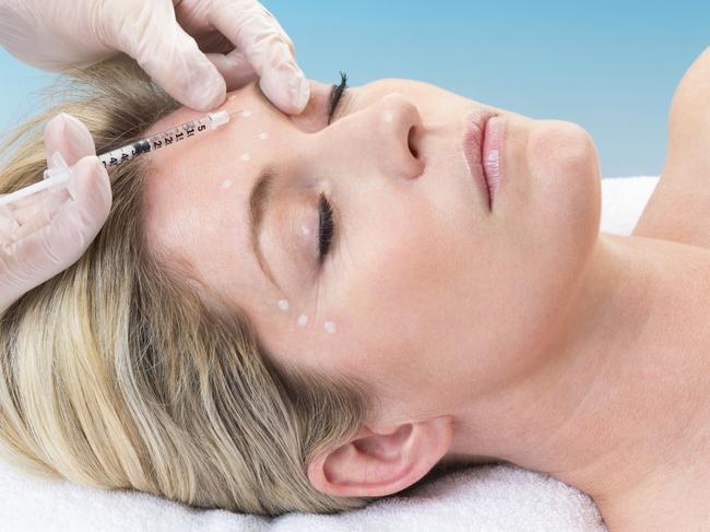 Woman lying down receiving botox injection in her forehead.