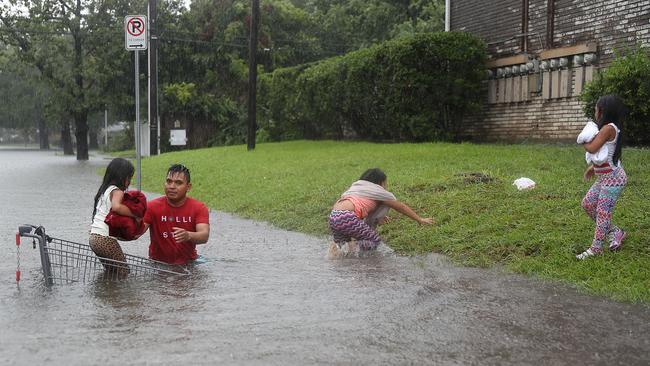 A man helps children across a flooded street as they evacuate their home. Picture: Joe Raedle/Getty Images/AFP