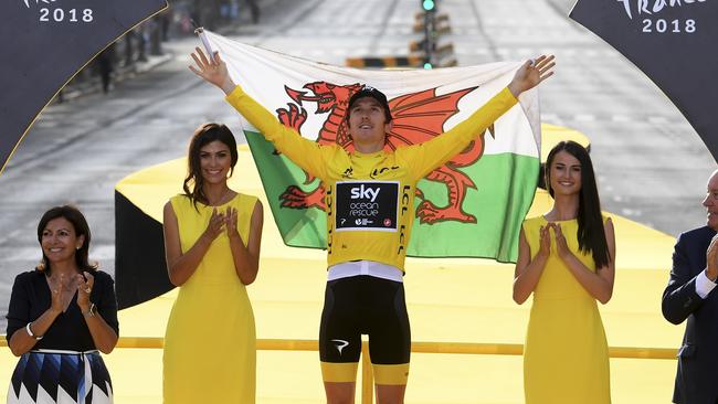 Tour de France winner Britain's Geraint Thomas, wearing the overall leader's yellow jersey, and draped in the flag of Wales celebrates on the podium after the twenty-first stage of the Tour de France cycling race over 116 kilometers (72.1 miles) with start in Houilles and finish on Champs-Elysees avenue in Paris, France, Sunday July 29, 2018. (Stephane Mantey, pool via AP)