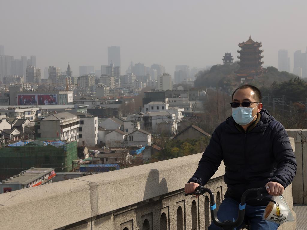 A Chinese man wearing a face mask as he rides an electric bike across the Yangtze River in Wuhan, China. Picture: Lintao Zhang