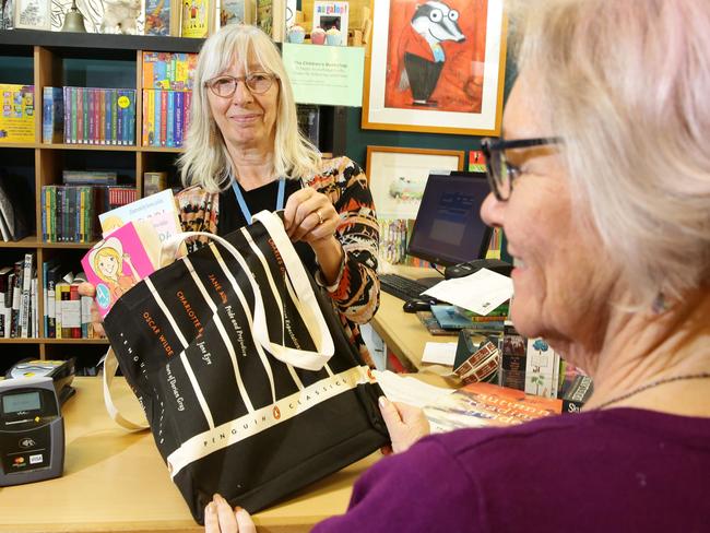 Shop assistant Ann Kliem provides a reusable bag to a customer at The Childrens Bookshop at Beecroft. Picture: Mark Scott