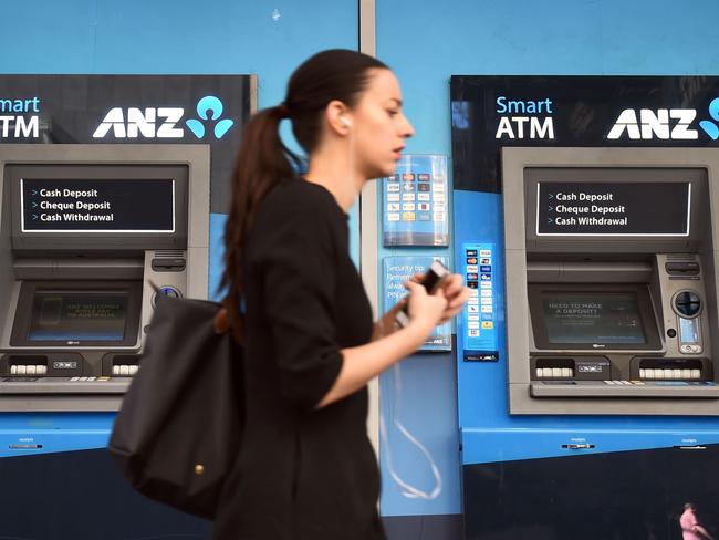 A woman walks past ANZ Bank automatic teller machines (ATMs) in Sydney on May 3, 2016. ANZ Bank on May 3 posted an interim net profit slump of 22 percent on the back of impairment and restructuring charges that the lender said would reposition it for the future. / AFP PHOTO / WILLIAM WEST