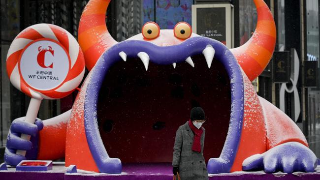 A woman wearing a face mask walks past a installation at a mall in Beijing. Picture: AFP