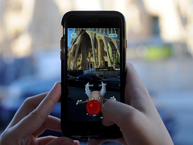 A young woman plays Pokemon Go in front of Sagrada Familia in Barcelona, Spain. Picture: Getty