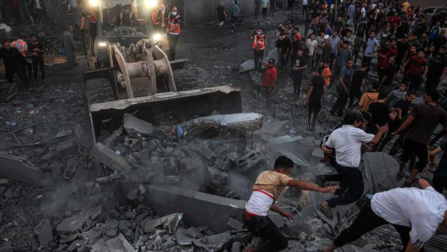 A bulldozer clears rubble as people gather in a neighbourhood in the southern Gaza Strip after it was hit by an Israeli strike on October 15. Picture: Said Khatib/AFP