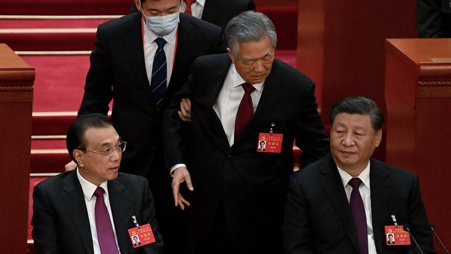 TOPSHOT - China's President Xi Jinping (R) sits besides Premier Li Keqiang (L) as former president Hu Jintao (C) is removed from the closing ceremony of the 20th China's Communist Party's Congress.