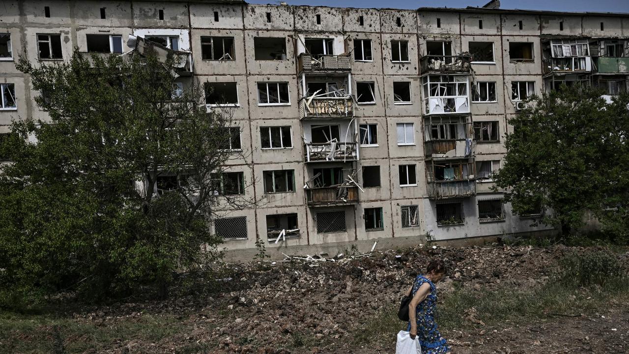 A woman walks in front of damaged apartment building after a missile strike in the city of Soledar, in the eastern Ukrainian region of Donbas on June 4, 2022. (Photo by ARIS MESSINIS / AFP)