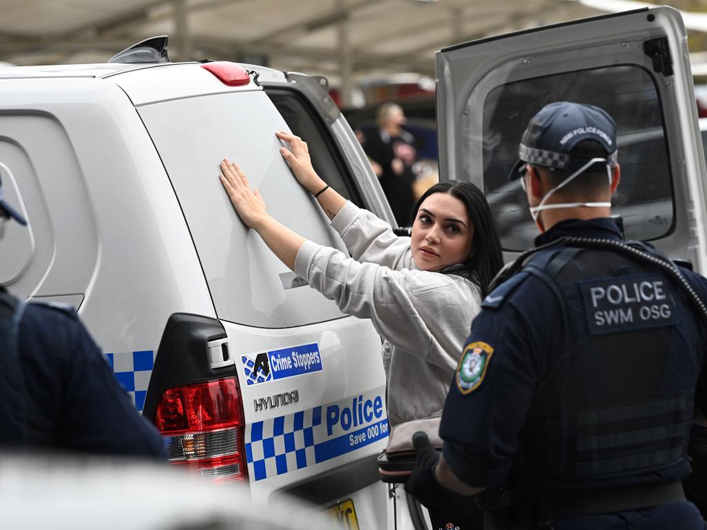 A woman detained and searched by police at Bass Hill Shopping Plaza after reports of a planned Freedom Rally march. Picture: NCA NewsWire / Jeremy Piper