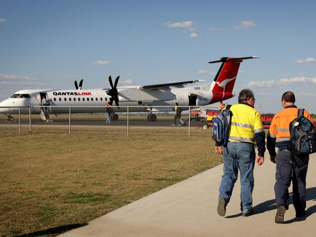 Fly In Fly Out (FIFO) miners walk out to their waiting QANTAS Dash 8 at Moranbah airport.