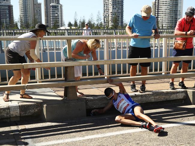 Callum Hawkins lies on the Sundale Bridge as concerned onlookers offer assistance. Picture: Cameron Spencer/Getty Images